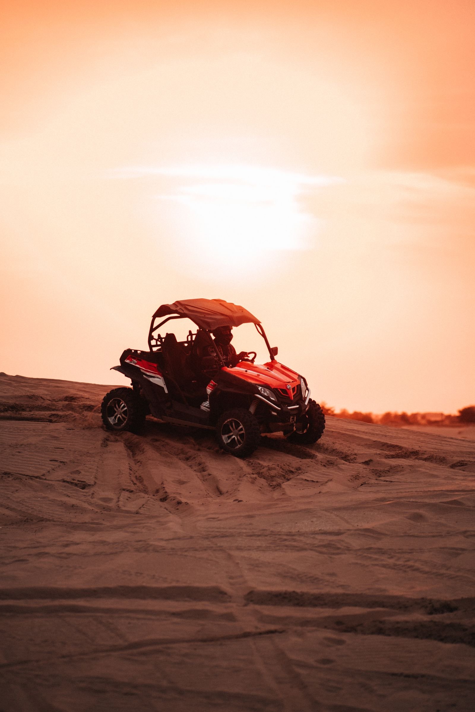 Red dune buggy driving in the desert at sunset