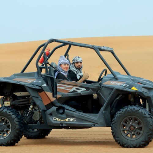 Couple driving a dune buggy in the desert