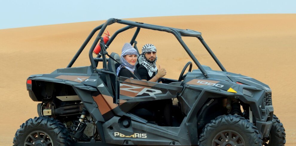 Couple driving a dune buggy in the desert