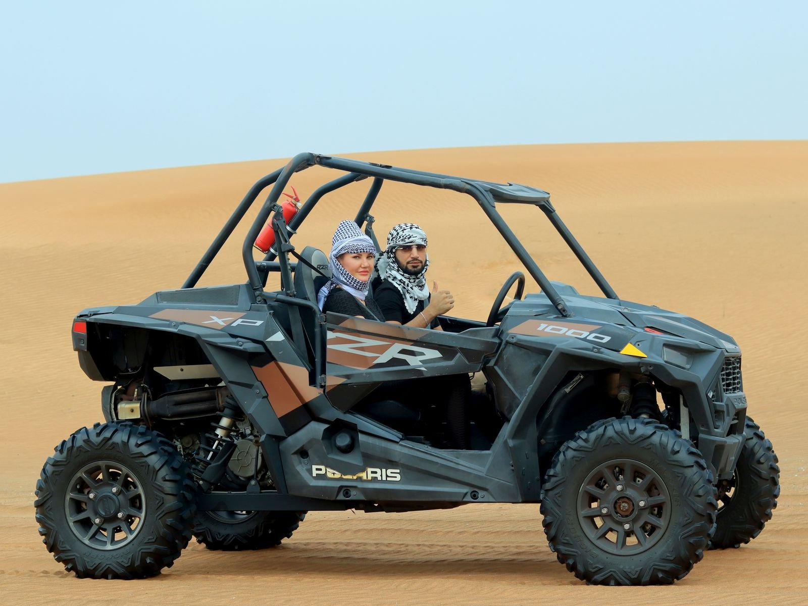 Couple driving a dune buggy in the desert