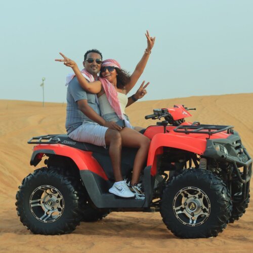 Couple riding a quad bike on a desert safari