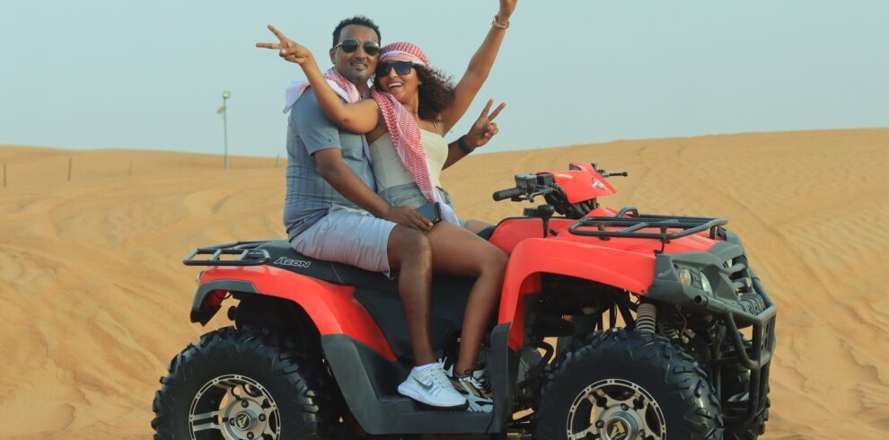 Couple riding a quad bike on a desert safari