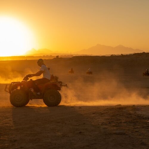 Quad bikes riding through the desert at sunset