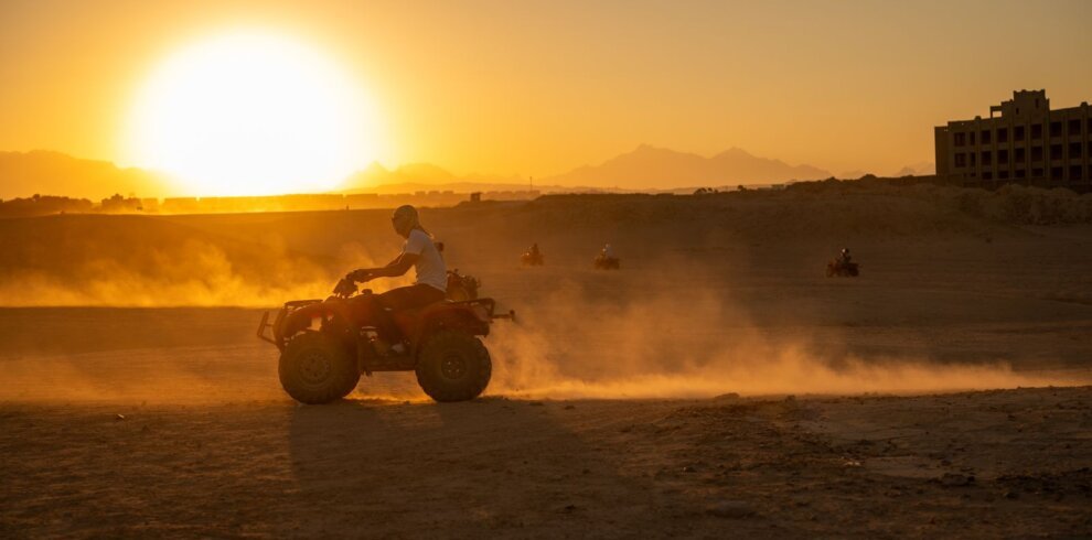 Quad bikes riding through the desert at sunset