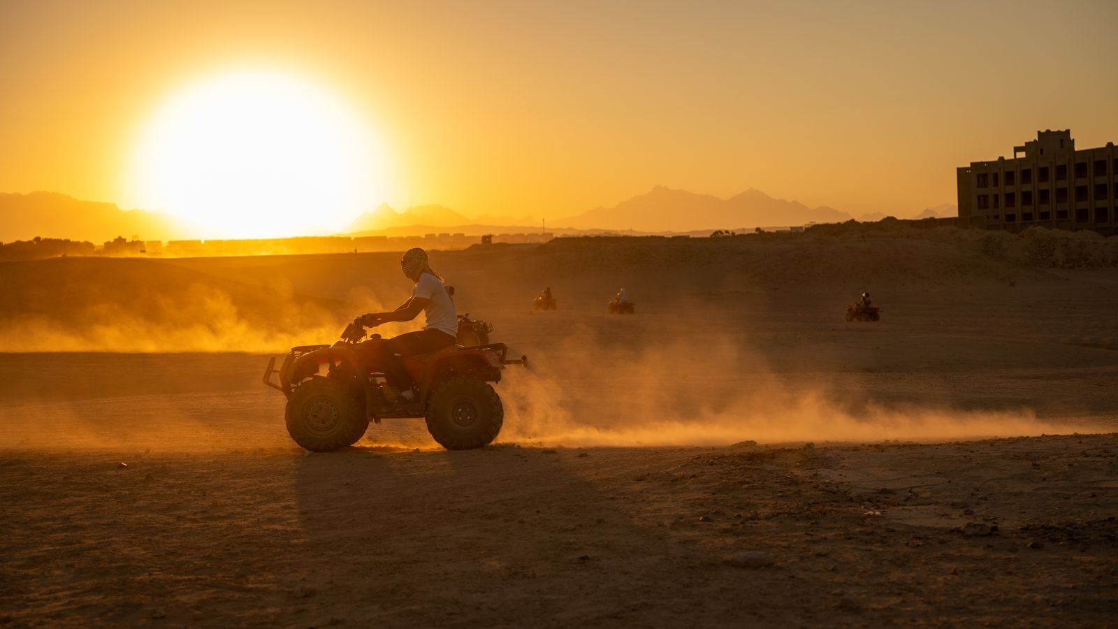 Quad bikes riding through the desert at sunset