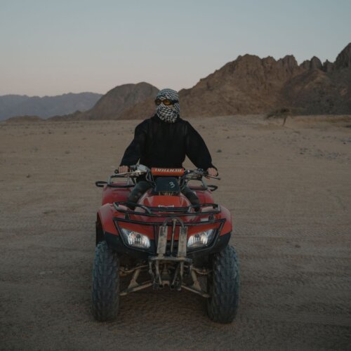 Rider on a red quad bike in the rocky desert mountains