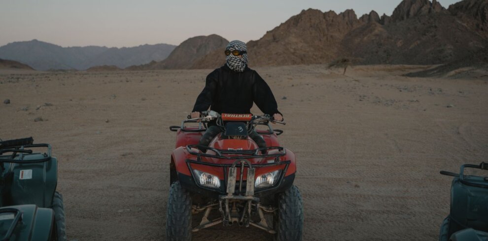 Rider on a red quad bike in the rocky desert mountains