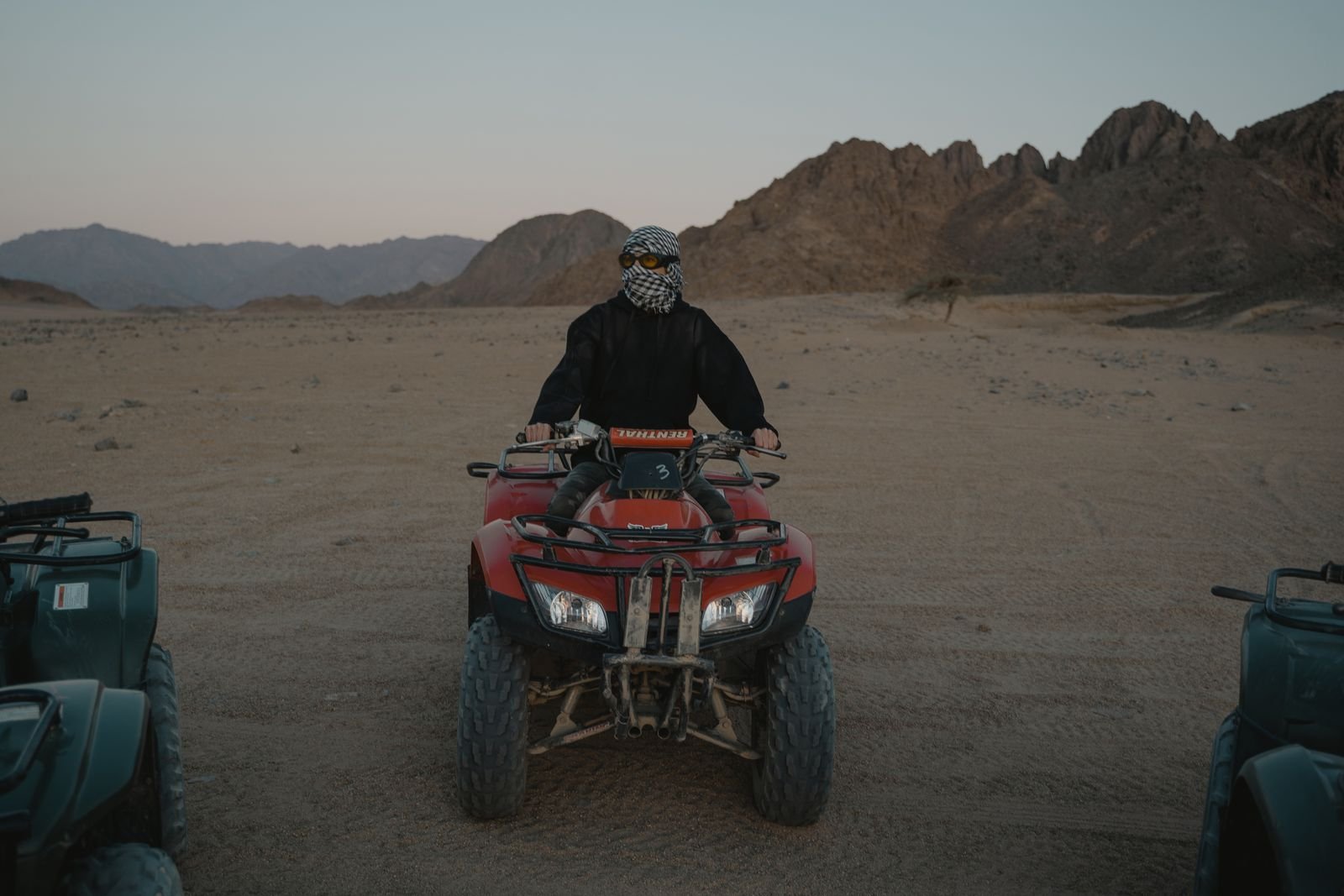Rider on a red quad bike in the rocky desert mountains
