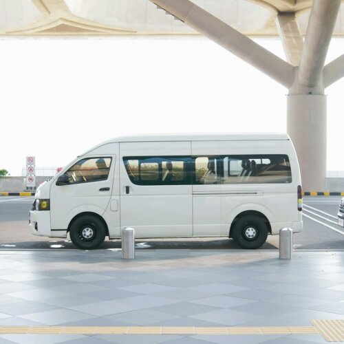 A white van at an airport terminal drop-off zone