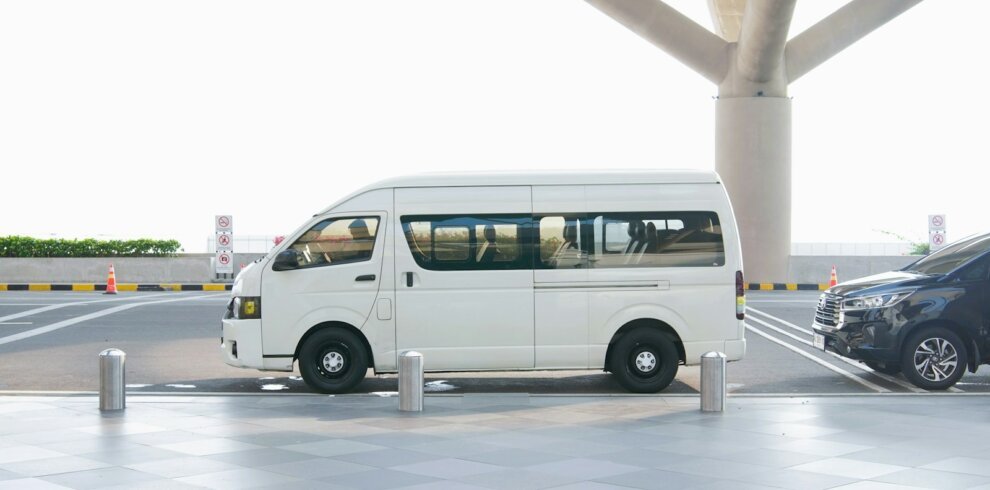 A white van at an airport terminal drop-off zone