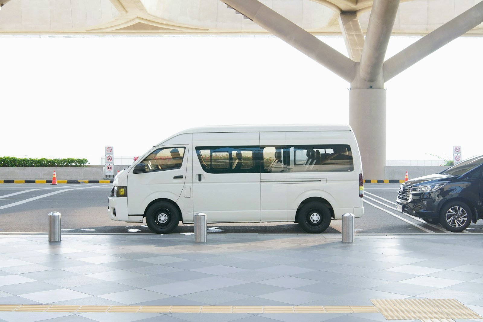 A white van at an airport terminal drop-off zone
